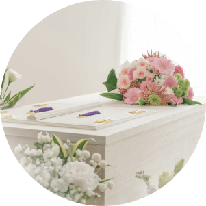 白木の棺にピンクの花束を載せた明るい葬儀イメージ